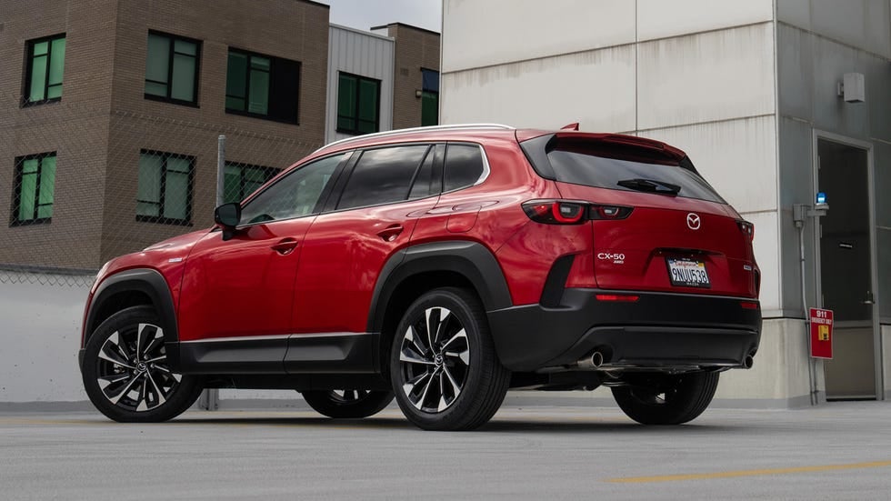 Rear-left view of a red Mazda CX-50 parked in an outdoor lot, showing its side profile and back.