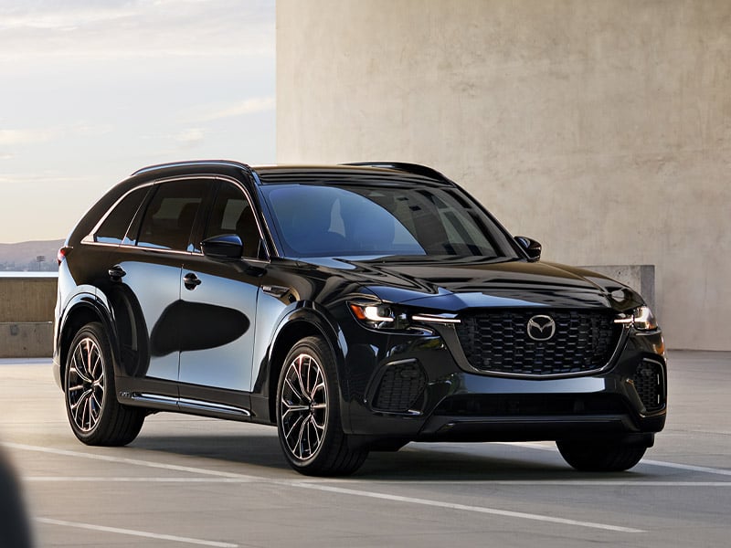 Front 3/4 view of a black 2024 Mazda CX-90 Premium SUV with metallic rims, parked on an asphalt lot.